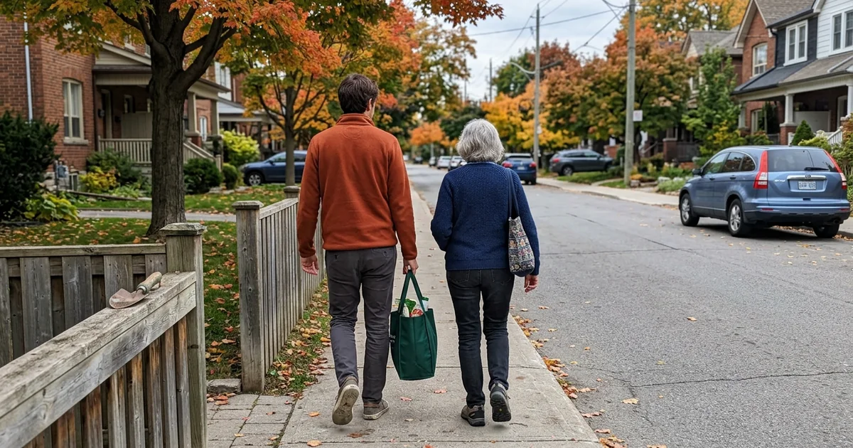 Adult son and senior mother walking together on a quiet Toronto street, seen from behind