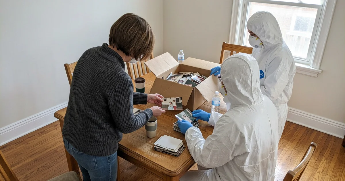 Crew members and a family member reviewing a box of photos, faces turned away