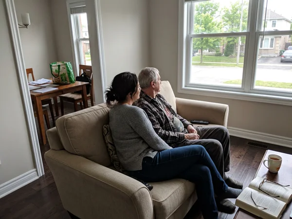 Adult child and senior parent on a clean sofa, seen from behind